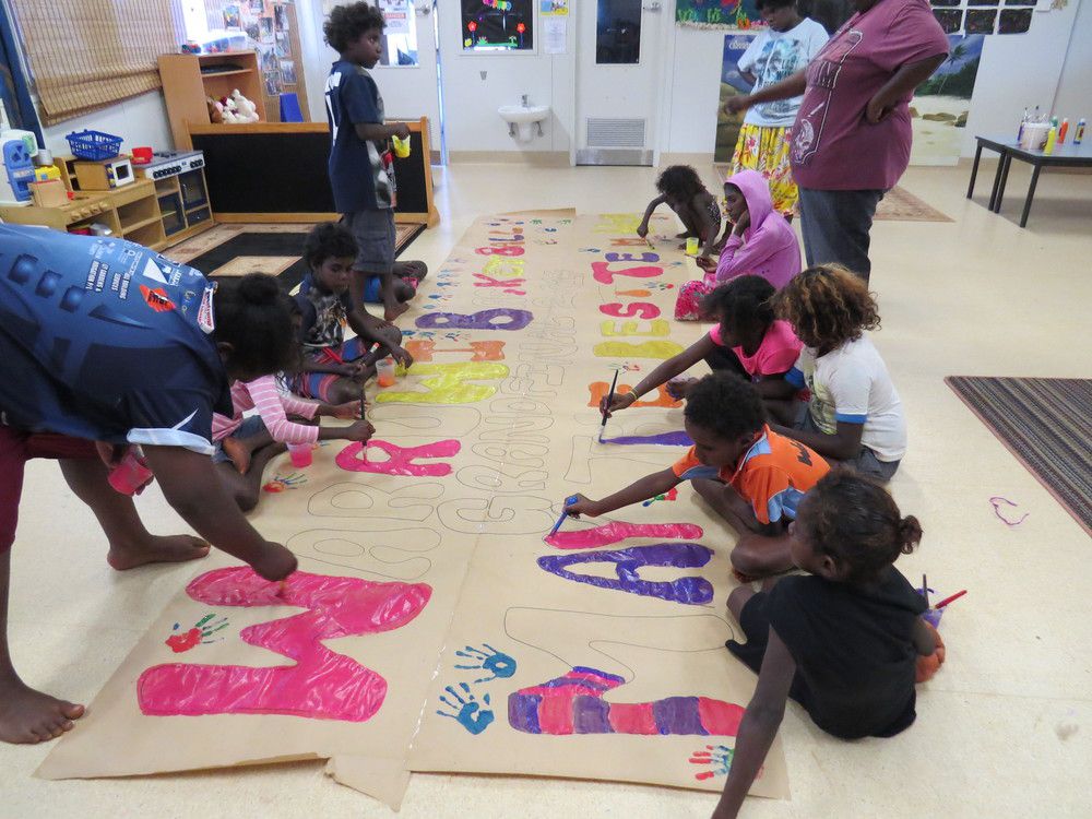 Kids at the Warruwi creche create a huge banner for the basketball finals event.