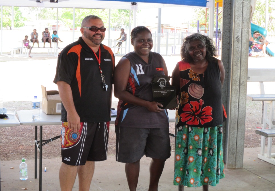 Warruwi's team captain Kylinda Brown (centre) receives the competition trophy on behalf of the team.