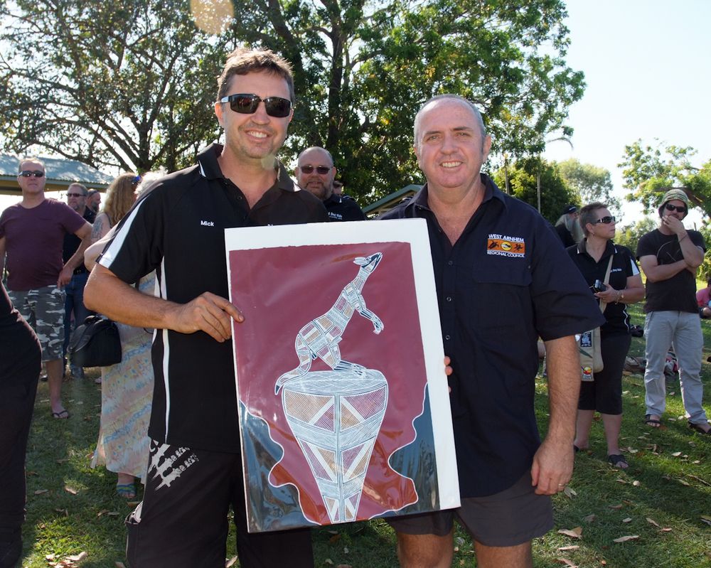 Black Dog Rider Mick Hutton from Jabiru Fire Station receives a ‘Dog Dreaming’ artwork from West Arnhem Councillor Peter Wilson at a free community breakfast put on to welcome the riders.